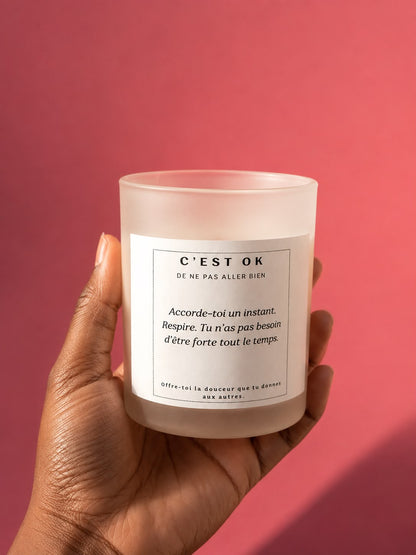 Bougie artisanale Mademoiselle Forte en cire de soja avec le message « C’est OK de ne pas aller bien », parfum framboise, dans un pot en verre givré.