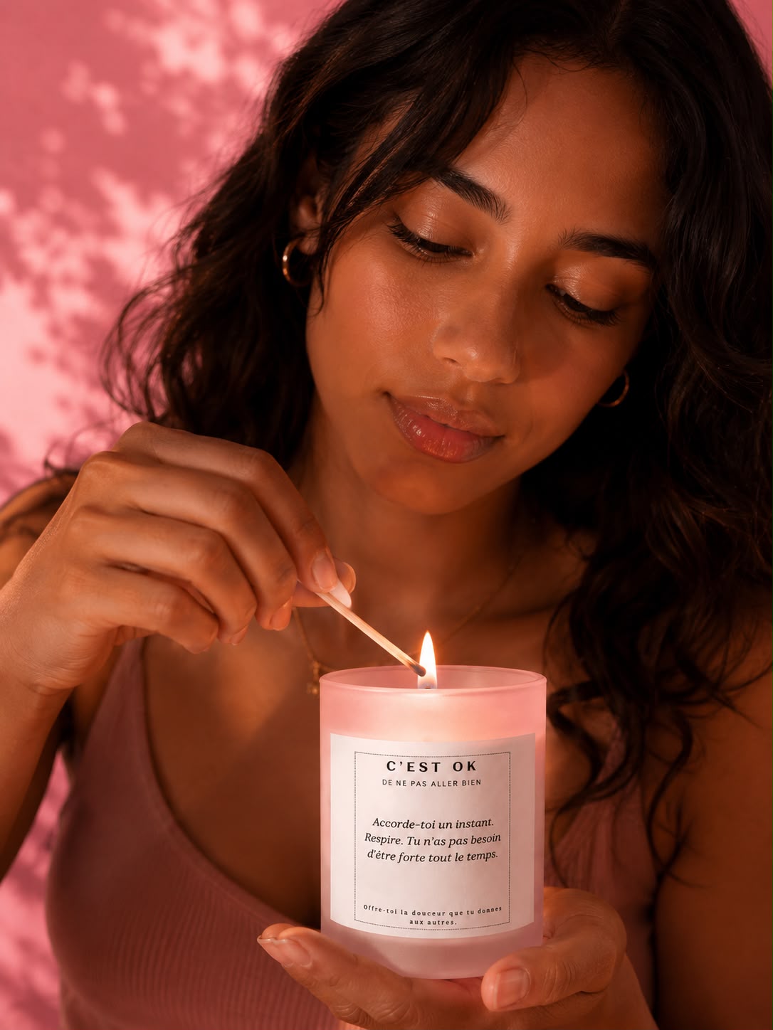 Une femme brune allume une bougie artisanale parfum fleur de cerisier Mademoiselle Forte dans un moment de calme, de douceur et de reconnexion à soi.