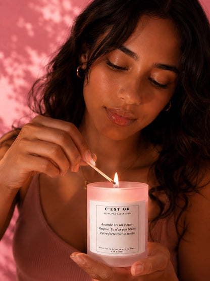 Une femme brune allume une bougie artisanale parfum fleur de cerisier Mademoiselle Forte dans un moment de calme, de douceur et de reconnexion à soi.